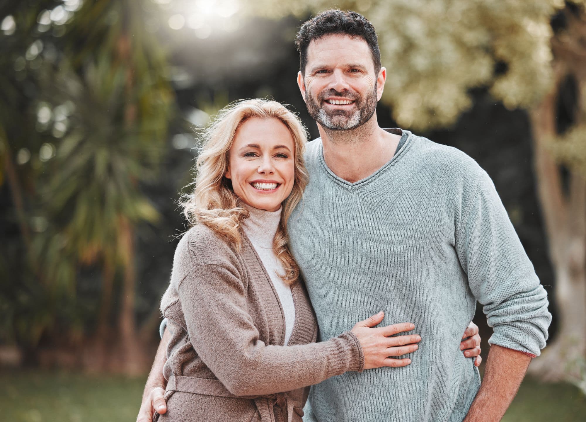 Un couple souriant se tient enlacé dans un jardin